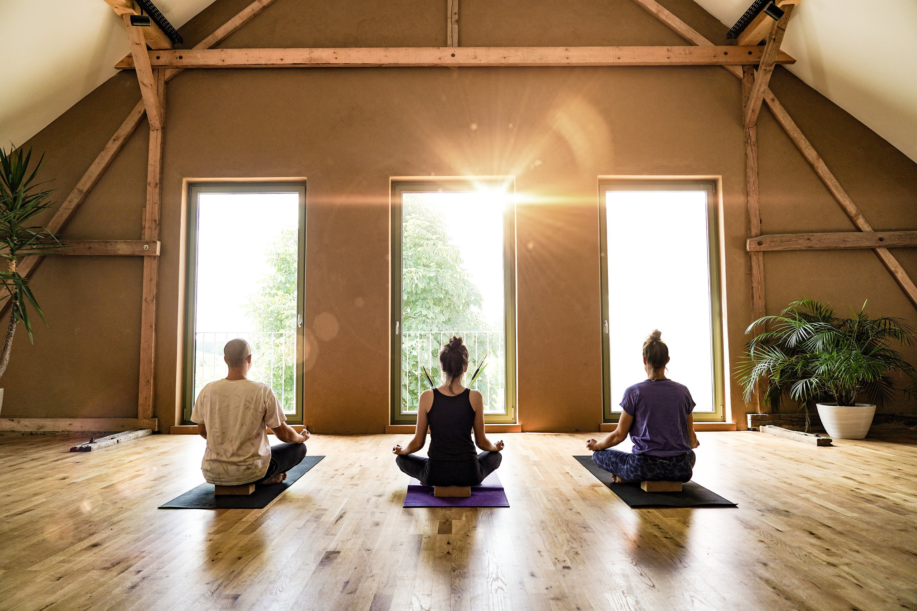 3 Menschen praktizieren Yoga.